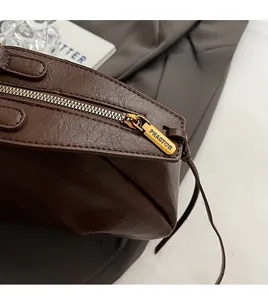 Vue détaillée de la fermeture éclair en métal doré et de la texture cuir du sac marron