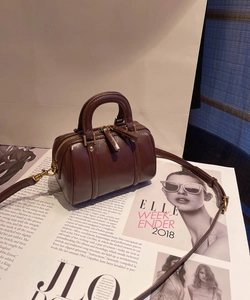 Detailed view of dark brown polished leather Boston bag with handles and strap on magazine