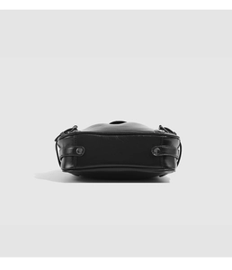 Detailed bottom view of black leather shoulder bag with smooth curves and metal rivets