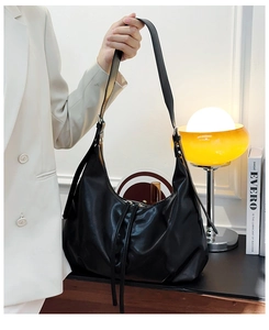 Detail of soft leather texture and adjustable strap on the black commuter tote bag