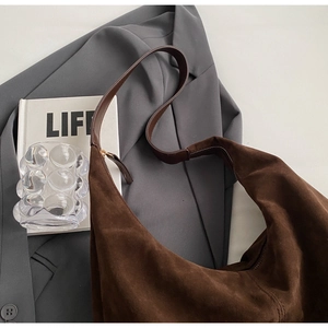 Détail d'un sac cabas hobo en daim marron foncé avec texture mate et fermeture éclair dorée