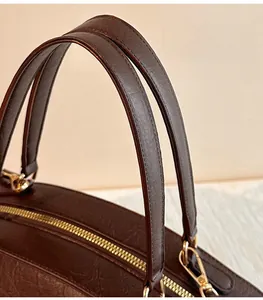 Détail d'un sac à main en cuir marron foncé avec poignées rondes et accents dorés