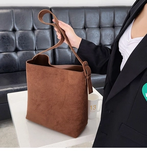 Detail of large brown suede bucket bag with adjustable strap and spacious interior