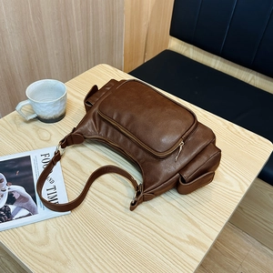 Retro brown leather shoulder bag with multi-functional zipper pockets on wooden table