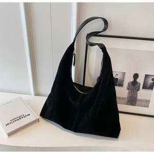 Détail du sac hobo en daim noir avec fermeture éclair dorée et texture premium