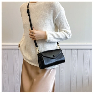 Classic black crossbody bag with flap closure and gold hardware on model background