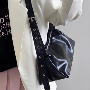 Glossy black half-moon shoulder bag with adjustable wide strap and silver metal eyelets