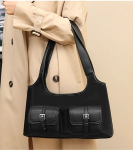 Detail of a black leather motorcycle bag featuring dual front pockets and silver buckles