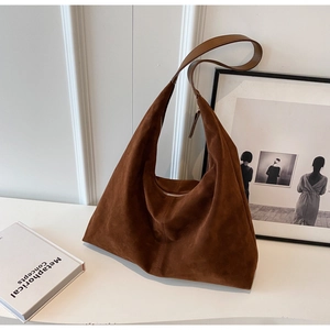 Gros plan d'un sac hobo en daim marron foncé avec une large bandoulière