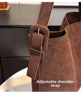 Close-up of adjustable wide shoulder strap with metal buckle on large brown suede tote