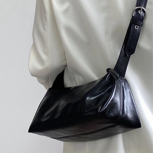Glossy black underarm bag with wide adjustable strap worn with a white blazer