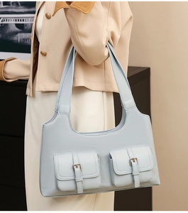Detail of light blue vintage hobo bag featuring dual front utility pockets and metal buckles