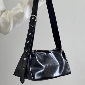 Minimalist black glossy shoulder bag with wide grommet strap and metallic hardware