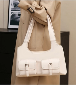 Close-up of cream motorcycle bag with double pocket design and matte faux leather texture