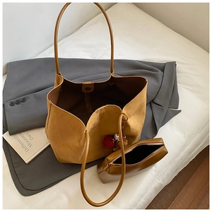 Detail view of khaki suede tote bag with matching inner pouch and plush ball accessory