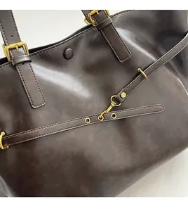 Detail of dark brown leather tote featuring vintage gold hardware and snap button