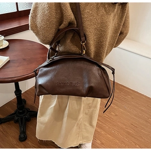 Détail du logo PNAOTOR sur un sac bowling vintage en cuir marron foncé gaufré