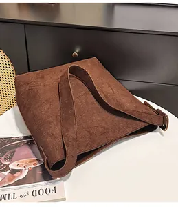 Close-up of brown suede tote bag with wide strap on a table for daily commute
