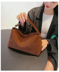 Detail of dark brown matte suede handbag with leather handle and smooth zipper closure