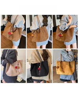 Detail view of large capacity suede tote bags in various colors with decorative pompom charms