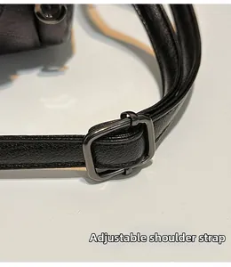 Dettaglio della tracolla regolabile con fibbia in metallo scuro su borsa in pelle nera