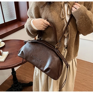 Gros plan détaillé du sac à main en cuir marron foncé avec lettrage embossé et texture fine