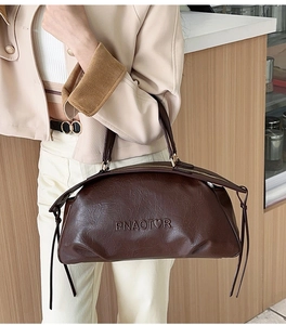 Détail de la texture cuir ciré marron foncé et logo PNAOTOR embossé sur le sac à main chic
