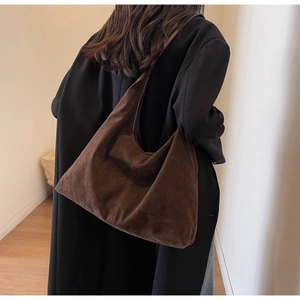 Détail d'un grand sac hobo en daim marron foncé porté pour un style vintage minimaliste