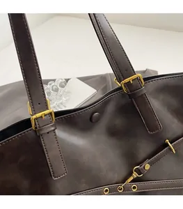 Close-up of vintage brown PU leather tote bag with elegant gold metal buckle detail