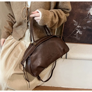 Détail du sac en cuir grainé café foncé avec logo embossé et bandoulière élégante