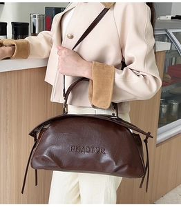 Détail du logo PNAOTOR embossé sur un sac Boston marron foncé avec accents de glands