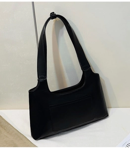 Detail of minimalist black faux leather shoulder bag with functional front patch pocket