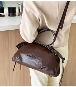 Modèle portant un sac bandoulière vintage marron foncé avec logo PNAOTOR et texture cuir