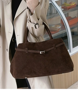Détail d'un sac cabas marron mat avec boucle métallique sur un trench-coat beige