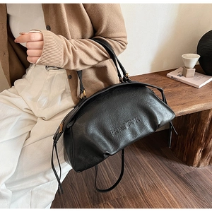 Gros plan d'un sac bowling en cuir noir avec logo embossé et texture grainée