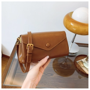 Detail view of a vintage dark brown leather shoulder bag with circular buckle and adjustable strap