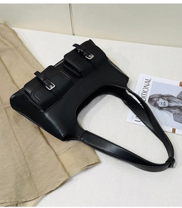 Detail of vintage black leather shoulder bag with functional dual pockets and silver buckles