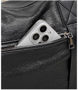 Close-up of black leather handbag side pocket with silver zipper showing interior capacity