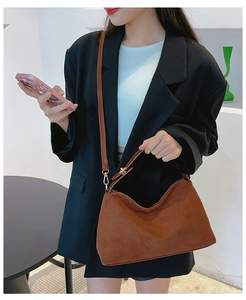 Brown matte suede crossbody bag shown with a short handle and adjustable strap on a model
