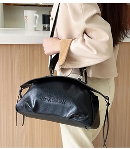 Détail du sac à bandoulière en cuir noir texturé avec le logo PNAOTOR embossé