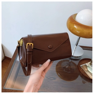 Detail of vintage brown envelope flap bag with polished gold-tone metal buckles