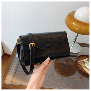 Detailed close-up of a vintage black leather crossbody bag with a golden strap buckle