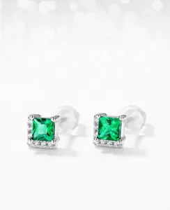 Macro detail of square emerald earrings with sparkling halo setting and silicone backings