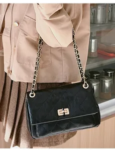 Close-up of elegant black quilted chain bag with gold twist lock on a shoulder strap