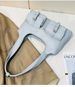 Detail view of sky blue hobo bag showing two front flap pockets and smooth PU leather