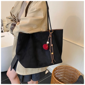 Close-up of black matte large tote bag with red pom-pom and wooden bead tassel
