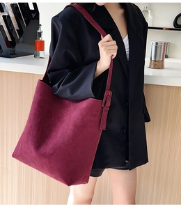Close-up of burgundy frosted suede tote bag with adjustable strap in casual setting