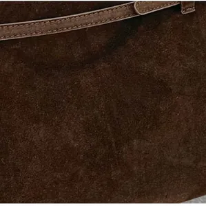 Vue détaillée de la texture en daim marron foncé et de la sangle d'un cabas classique
