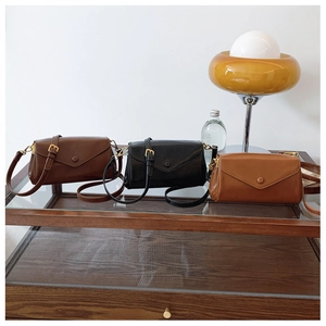 Detailed view of vintage envelope crossbody bags in dark brown, black, and caramel colors