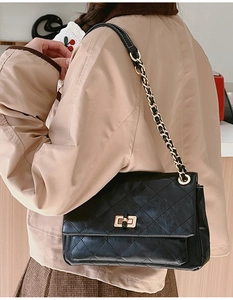 Detail of black quilted chain bag featuring golden twist lock and textured PU leather